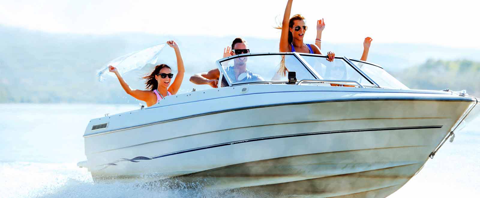 Group of young people riding in a boat on a lake.