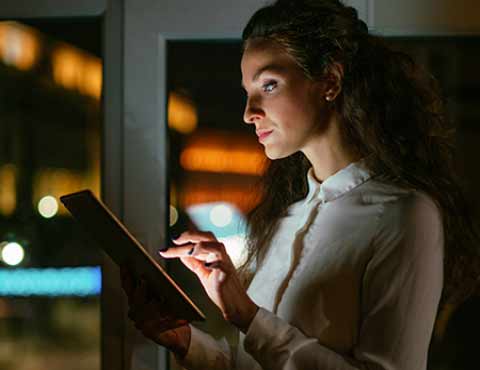 Person working on a tablet at night.