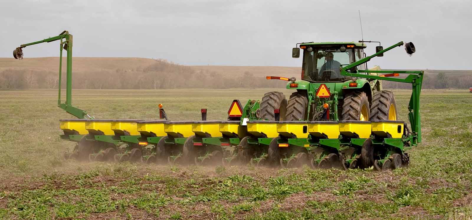 Tractor pulling harvesting equipment in a field.