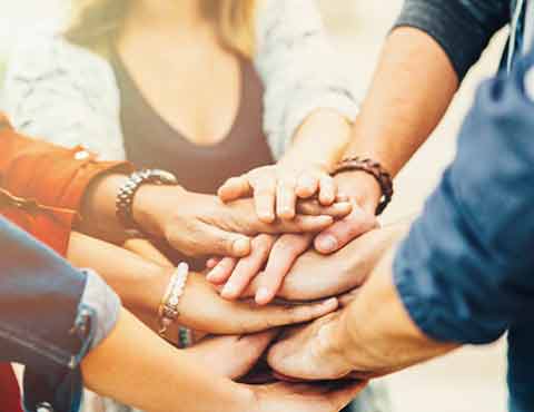 Group of people stacking hands in the middle.