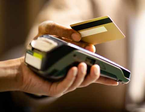 Person swiping a credit card through a credit card machine.